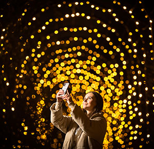 A woman takes a selfie in an illuminated tunnel at The Trentham Estate, Staffordshire