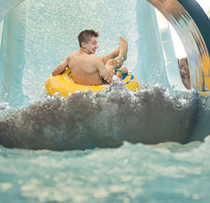 Image shows a man zooming down a flume on a big rubber ring at Waterworld, Stoke-on-Trent