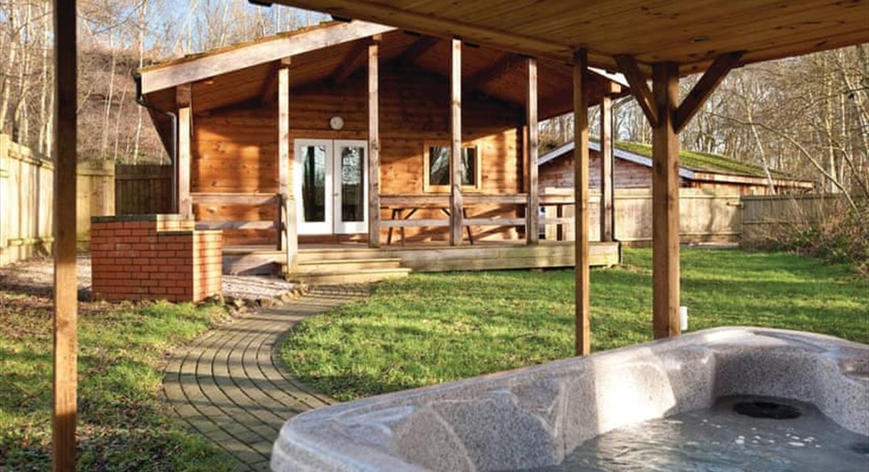 A hot tub on the porch of one lodge, looking over at another cabin, on a sunny day