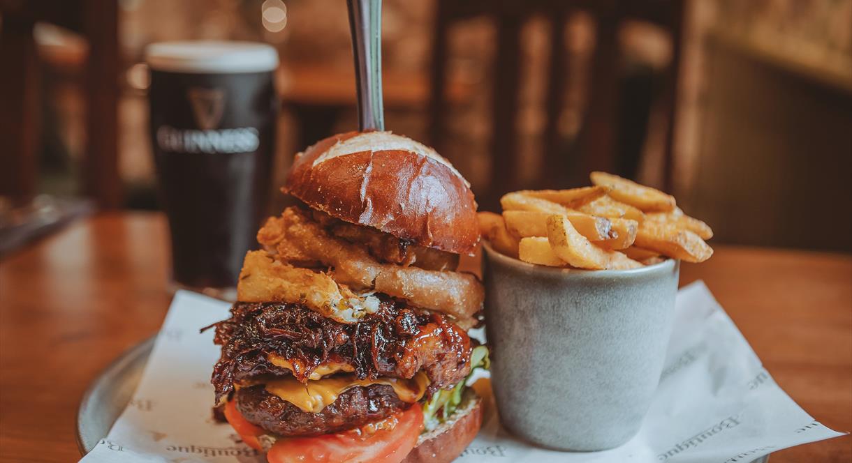 A burger and chips, with a nicely-poured pint of Guinness in the background