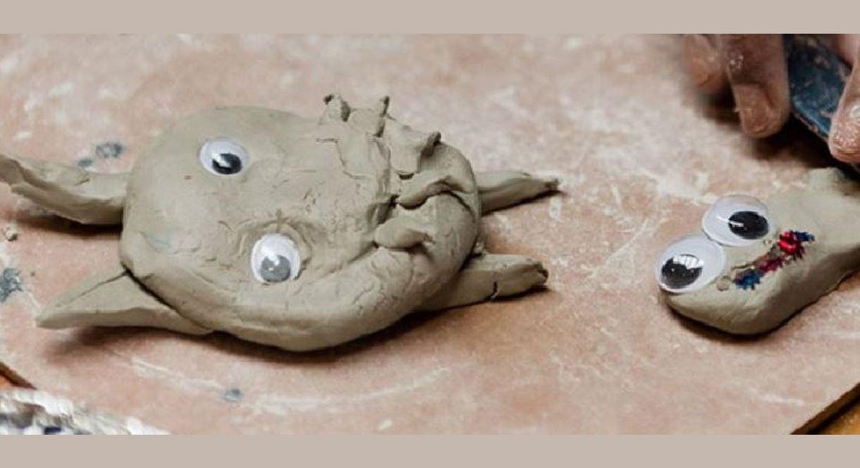 Two small clay creations with googly eyes placed on a work surface. One of them is decorated with colourful details.