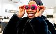 A smiling woman tries on some sunglasses
