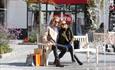 A couple takes a break from shopping on a bench and watches a fountain