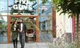 A smiling couple, with coffees and shopping bags in hand, leave Five Guys after a satisfying meal