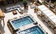 An image from above, showing the spa terrace at Hoar Cross Hall on a sunny day, with two inviting looking pools, a luxurious corner sofa, and seven be